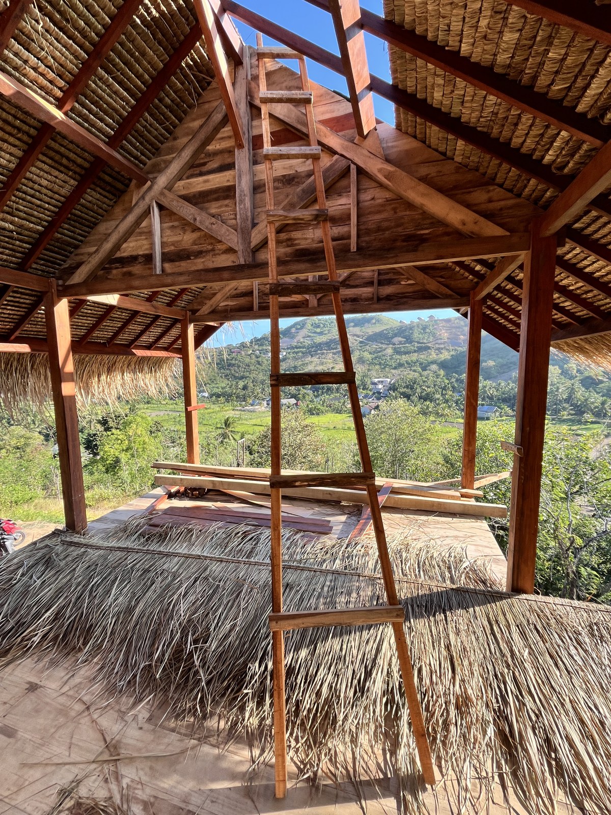 Interior en obra con techo de thatch y vista al valle