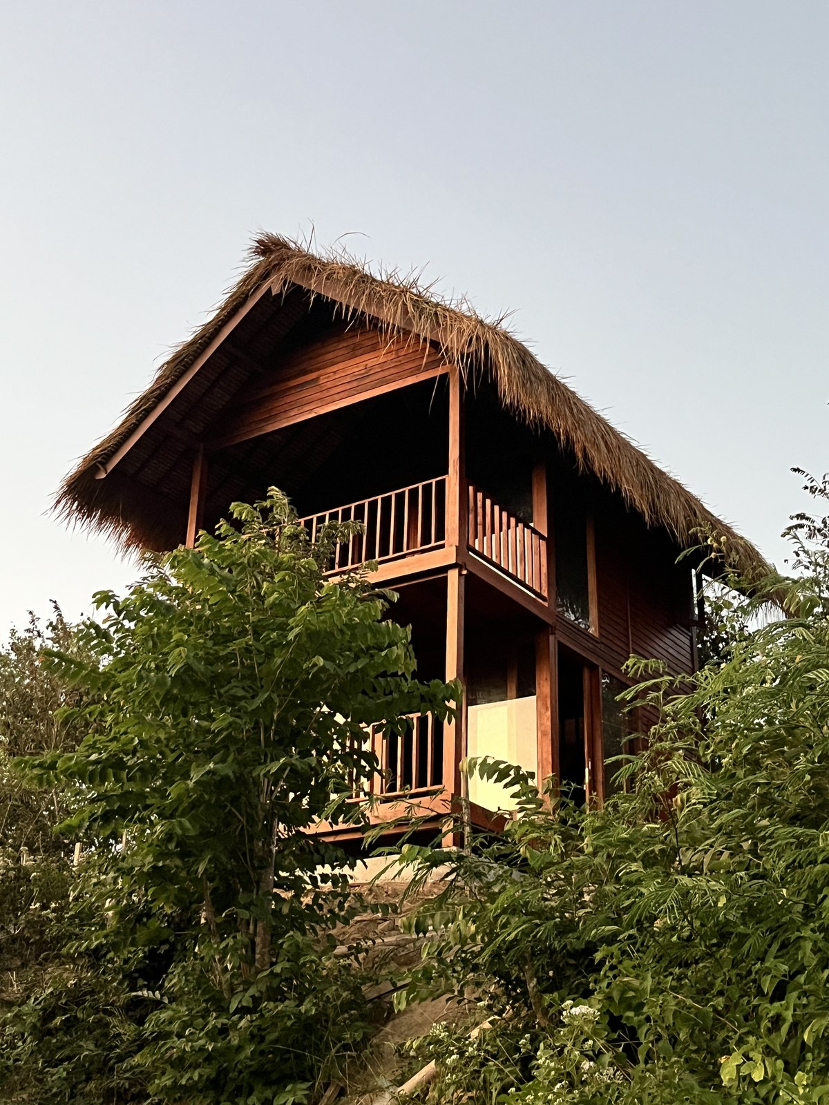 Casa Rumah Panggung de dos niveles con techo de thatch y balcones de madera
