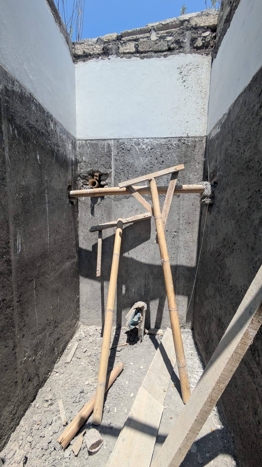 Baño en obra con muros de bloque y andamio de bambú